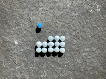 Colourful marbles arranged on a five by five grid. There's a single blue marble in the first row and in the first column. There is no second row. In the third row the first two columns are empty, the remaining columns are occupied by white marbles. The fourth and fifth rows are filled with white marbles.