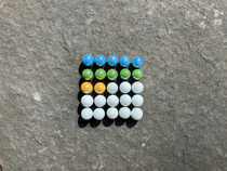 Colourful marbles arranged on a five by five grid. The first row is filled with blue marbles. The second row is filled with green marbles. In the third row the first two columns have yellow marbles in them, the remaining columns are occupied by white marbles. The fourth and fifth rows are filled with white marbles.