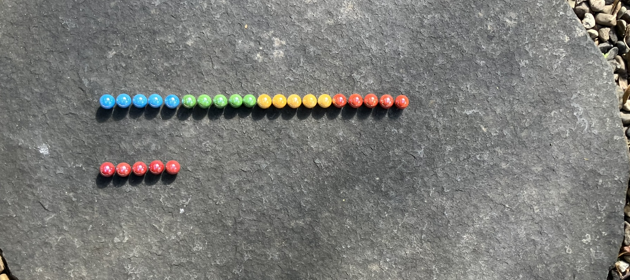 Colourful marbles, arranged on a mostly five by five grid. The first row is twenty marbles wide, the second, third and fourth rows are missing, they have been moved to the first row.