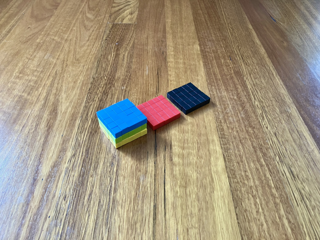 Colourful magnetic blocks, arranged in a rectangular prism, five wide, five high and three deep. Each layer has a different colour of magnetic block. Top to bottom it goes: blue, green and yellow. Two five by five squares of blocks sit just behind, one red and one black.