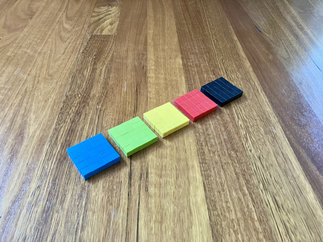 Five five-by-five squares of magnetic blocks laid out in a line. Each has a different colour of block: blue, green, yellow, red and black.